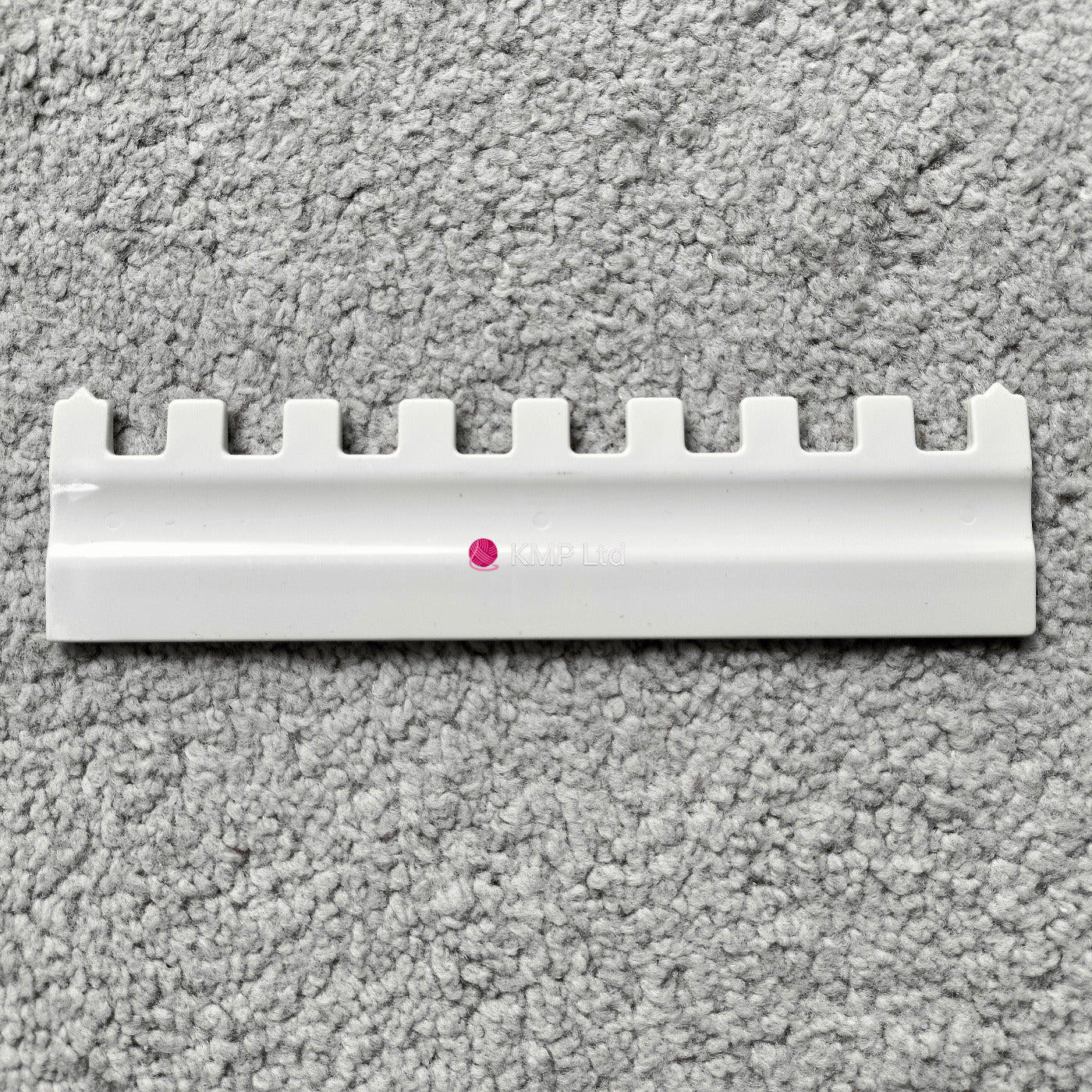 A Silver Reed SK 890 white needle pusher for an electronic knitting machine, placed on a grey surface. Main image