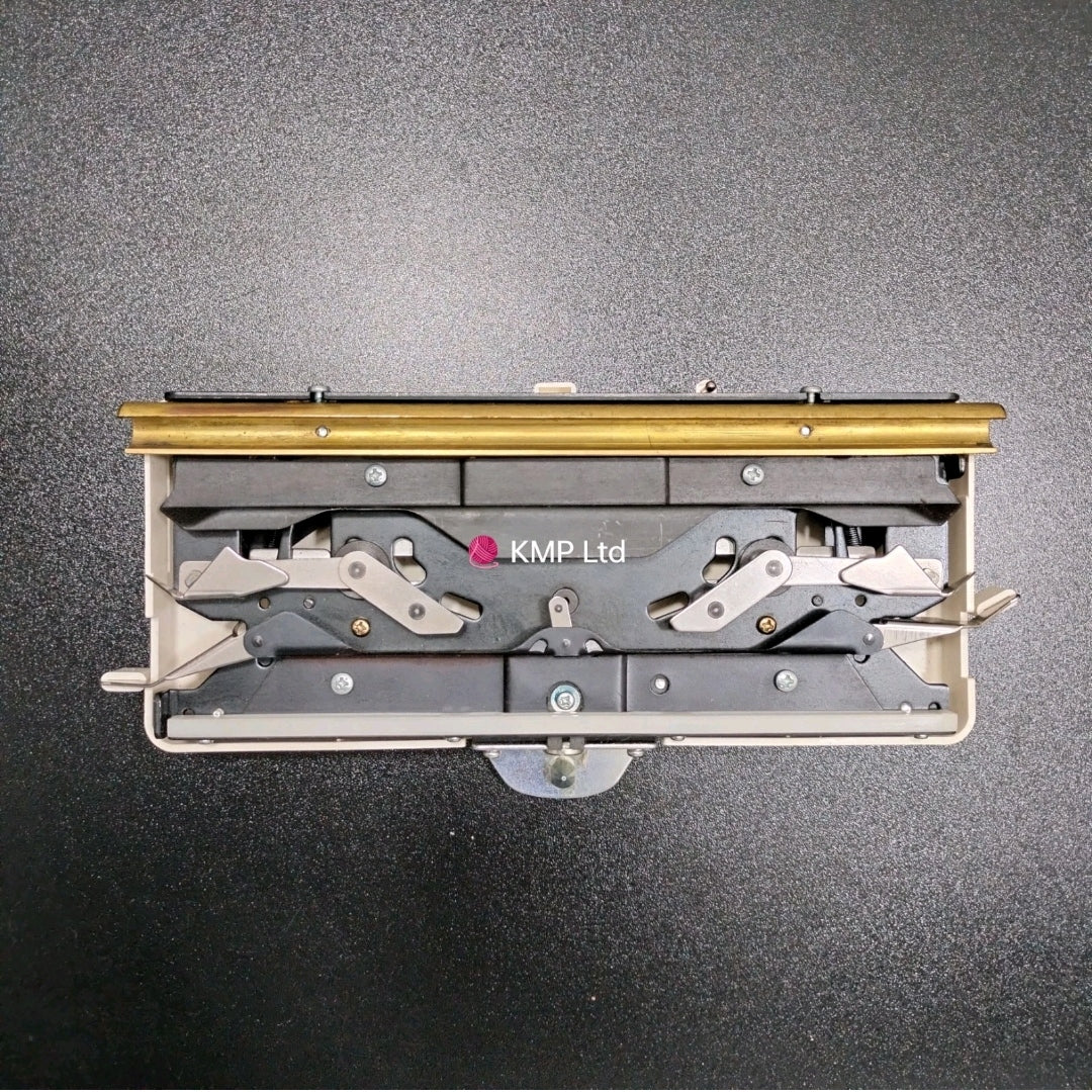 A Silver Reed standard gauge knitting machine ribber carriage potograhed on a black background