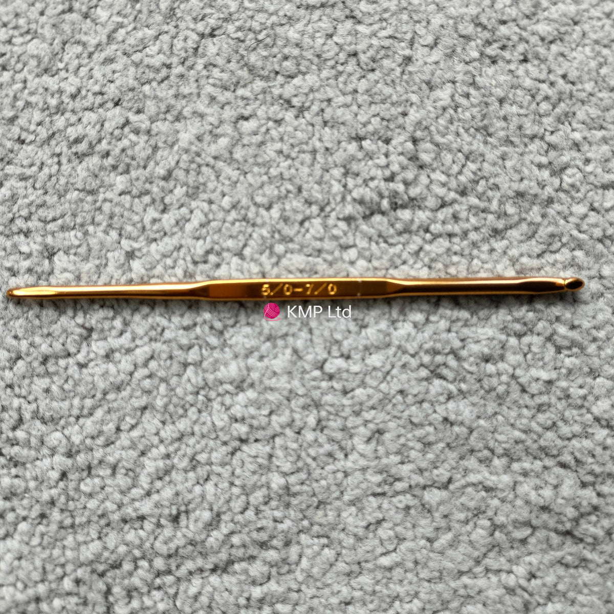 silver reed sk 890 chunky electronic-knitting machine crochet hook with '5-6' and '07' engraved on it, placed on a grey textured surface.