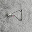 Silver Reed SK 890 Yarn Guide this a metallic yarn guide part for an electronic knitting machine, with a small amount of white yarn attached, placed on a grey background.