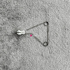 Silver Reed SK 890 Yarn Guide this a metallic yarn guide part for an electronic knitting machine, with a small amount of white yarn attached, placed on a grey background.