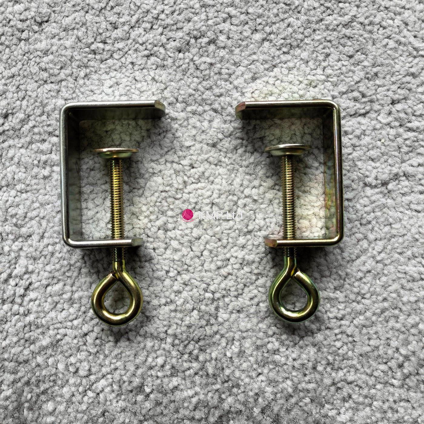 Silver Reed SK 890 Brass-colored table clamps for an electronic knitting machine, placed on a grey background. Main image