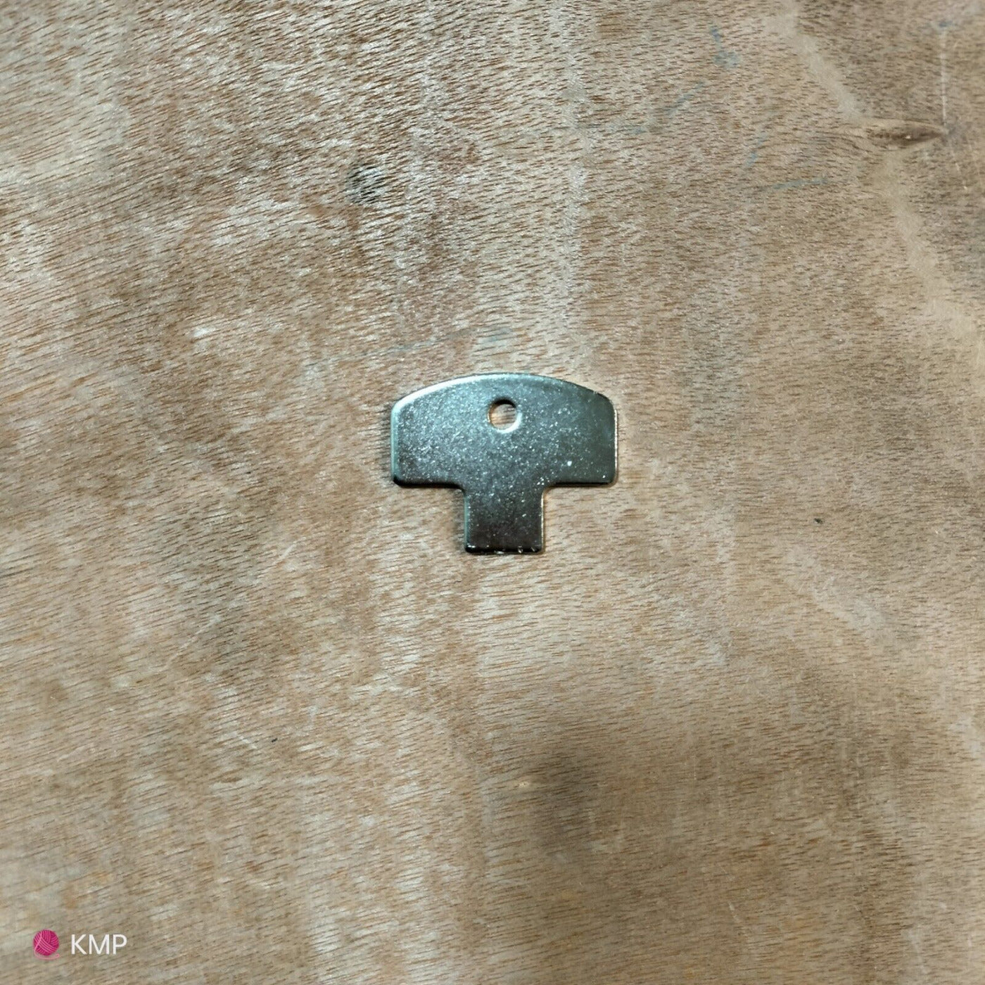 A close-up image of a Silver Reed SRP-60N Ribber Screw Driver, showing a silver-colored metal tool with a visible screw hole, placed on a wooden surface. Main image